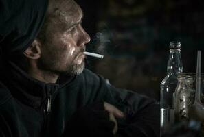 obdachlos Männer mit Zigarette und Flasche von Wodka foto