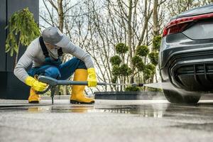 Männer Druck Waschen seine Auto im Vorderseite von ein Haus foto