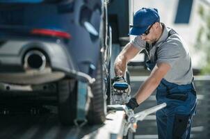 Abschleppen Unternehmen Arbeiter Sicherung Fahrzeug auf das LKW Plattform foto