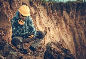 kaukasisch männlich Ingenieurwesen Geologe reden auf Radio beim Konstruktion Seite? ˅. foto