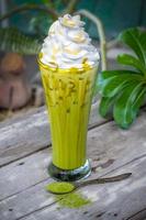 Eis Matcha grüner Tee mit Schlagsahne auf hölzernem Tischhintergrund foto