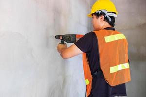 Der Mechaniker bohrt die Betonwand foto