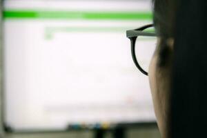 Arbeiten Frauen aussehen beim Computer Monitore Sitzung beim Schreibtisch, mit Laptop foto