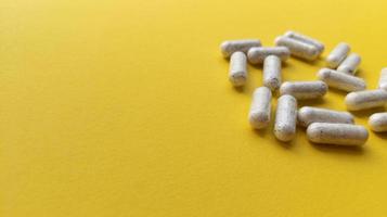 weiße Pillen auf gelbem Hintergrund einfache flache Lage mit Pastellbeschaffenheit und kopieren Raum medizinisches Konzept stock photo