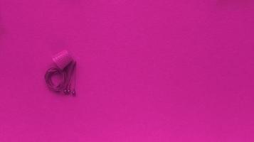 Fingerhutfaden und Sicherheitsnadel auf rosa Hintergrund monochrome einfache flache Lage mit Pastell Textur Mode Öko-Konzept stock photo