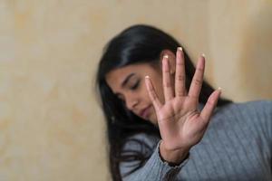 junge indische Frau der Selbstverteidigung, die ihr Gesicht mit Handfrau bedeckt, sagt halt foto