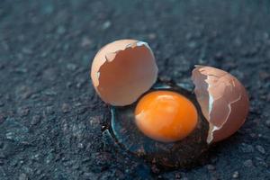 zerbrochenes Ei auf Asphalt als Symbol des Scheiterns