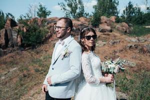 Hochzeitsfotografie modische Braut und Bräutigam in Sonnenbrille auf der Natur auf den Felsen