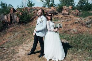 Hochzeitsfotografie modische Braut und Bräutigam in Sonnenbrille auf der Natur auf den Felsen