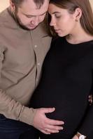 Ein junges Paar erwartet von einem Baby ein schwangeres Mädchen in einem schwarzen Kleid