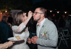 Die Braut und der Bräutigam auf der Party schneiden und probieren die Hochzeitstorte foto