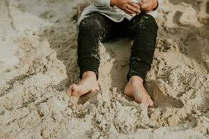 Detail von Mädchen Beine mit schmutzig Füße von Sand Standort und graben im Sand während das sonnig Sommer- Tag foto