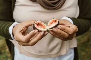 zwei Hälften von ein frisch, saftig und Süss rot und violett Feige frisch gepflückt von das Baum, halten im Frau Hände foto