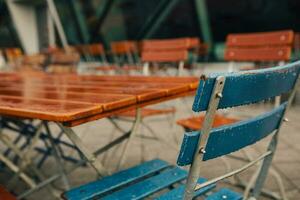 das Ende von Jahreszeit im Bier Garten mit Regen fallen auf hölzern Stuhl während spät Herbst Morgen foto