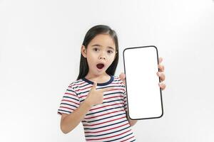 asiatisch wenig Mädchen halten Smartphone Attrappe, Lehrmodell, Simulation von leer Bildschirm und lächelnd auf Weiß Hintergrund. foto