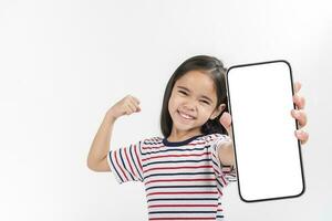asiatisch wenig Mädchen halten Smartphone Attrappe, Lehrmodell, Simulation von leer Bildschirm und lächelnd auf Weiß Hintergrund. foto