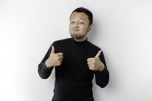 aufgeregt asiatisch Mann tragen schwarz Hemd gibt Daumen oben Hand Geste von Genehmigung, isoliert durch Weiß Hintergrund foto
