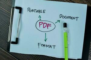 Konzept von pdf - - tragbar dokumentieren Format schreiben auf Papierkram isoliert auf hölzern Tisch. foto