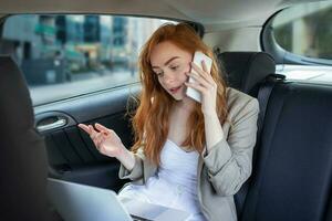 Geschäftsfrau reden auf das Handy, Mobiltelefon Telefon und mit das Laptop im das Auto foto