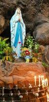 Statue von heilig Jungfrau Maria im römisch katholisch Kirche, im das Höhle von Jungfrau Maria, im ein Felsen Höhle Kapelle katholisch Kirche mit tropisch Blumen um foto