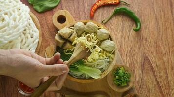 Frikadelle, im Indonesien bekannt wie Bakso oder Baso. serviert mit Nudeln Gemüse Chili Soße im ein Schüssel auf Weiß Hintergrund. schließen oben oben Aussicht eben legen foto