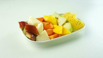 geschnitten Obst Salat, im Indonesien bekannt wie Rujak buah oder lutis oder Lotis. serviert mit würzig braun Zucker Soße und Boden Erdnüsse im ein Teller isoliert auf Weiß Hintergrund foto