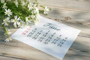 Juni Kalender und Weiß Blumen auf hölzern Hintergrund foto