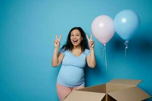 schön schwanger Frau drückt aus glücklich positiv Emotionen beim Geschlecht Party während Blau und Rosa Luftballons fliegen aus von ein Box foto