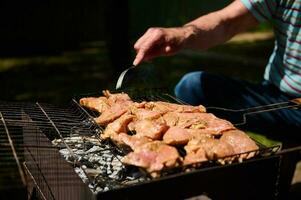 Nahansicht von Alten Mann Grillen Essen, Fleisch auf Grill foto