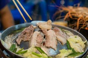 schließen oben gegrillt Schweinefleisch Fleisch auf heiß schwenken zum Kochen auf verschwommen Hintergrund, geröstet Fleisch auf Rauch schwebend im Restaurant. foto