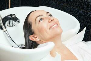 Weiß Frau bekommen ein Haar waschen Verfahren im ein Schönheit Salon foto