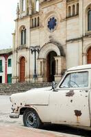 Antiquität rostig Auto geparkt Nächster zu das Gemeinde Kirche von das klein Stadt, Dorf von ventaquemada im Kolumbien foto