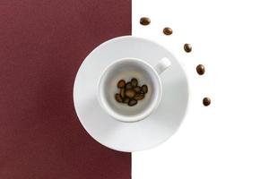 Draufsicht einer Kaffeetasse und von Kaffeebohnen auf braunem und weißem Hintergrund foto