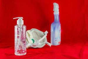 Desinfektionsgelmaske und antiseptisches Reinigungsspray auf rotem Schutzkonzept gegen Verschmutzungsvirusgrippe und Coronavirus foto