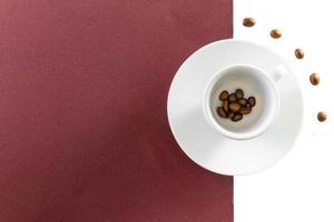 Draufsicht einer Kaffeetasse und von Kaffeebohnen auf braunem und weißem Hintergrund foto