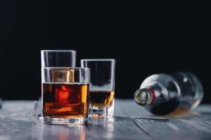 Stillleben mit verschiedenen Gläsern und Flaschen Alkohol auf Holztisch
