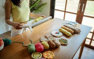 schlagen Nadel. asiatisch Frau Herstellung handgemacht Hobby Stricken im Studio Werkstatt. Designer Arbeitsplatz handgemacht Kunst Projekt DIY Stickerei Konzept. foto