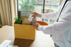 Verlassen Job Geschäft Mann Senden Rücktritt Brief und Verpackung Zeug zurücktreten drücken oder Tragen Geschäft Karton Box im Büro. Veränderung von Job oder gefeuert von Unternehmen. foto