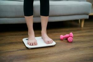 Fett Diät und Rahmen Füße Stehen auf elektronisch Waage zum Gewicht Kontrolle. Messung Instrument im Kilogramm zum ein Diät Steuerung foto
