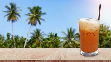 vereist thailändisch Milch Tee im Glas, Milch Eis Tee, Cheddar ist ein traditionell thailändisch trinken auf hölzern Tabelle mit Natur Hintergrund, Sommer- Getränke mit vereist foto