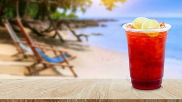 vereist Tee und Zitrone Scheiben auf hölzern Tabelle mit Strand Landschaft Natur Hintergrund, Sommer- Getränke mit Eis foto