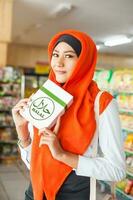 Muslim Frau Kauf halal Essen im ein Supermarkt foto