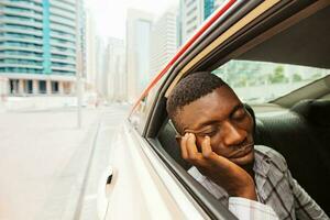 erschöpft jung afrikanisch Mann Schlafen im Taxi foto