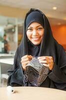 jung arabisch lächelnd Burka gekleidet Frau Nähen ein Schädeldecke foto