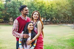 schön indisch Familie mit 10 Jahre alt Tochter Stehen zusammen im ein Park foto