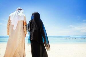 Muslim Paar auf ein Strand tragen traditionell Kleid foto