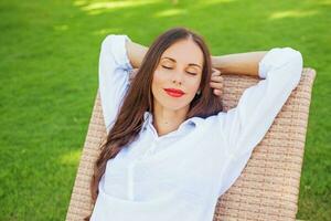 Frau entspannend im ein Liege Über Grün Gras foto