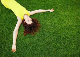 heiter Frau tragen hell Kleid Lügen Nieder auf ein Gras foto