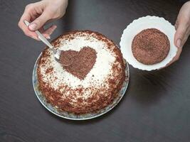 dekorieren ein Kuchen zum Valentinstag Tag. handgemacht Kuchen mit Sahne Käse Glasur und ein Schokolade Herz. Süßigkeiten zum Valentinstag Tag foto