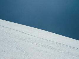 Ski Neigung. Schnee Berg und dunkel Blau Himmel. schön minimalistisch Landschaft von Weiß Schnee hügel. foto